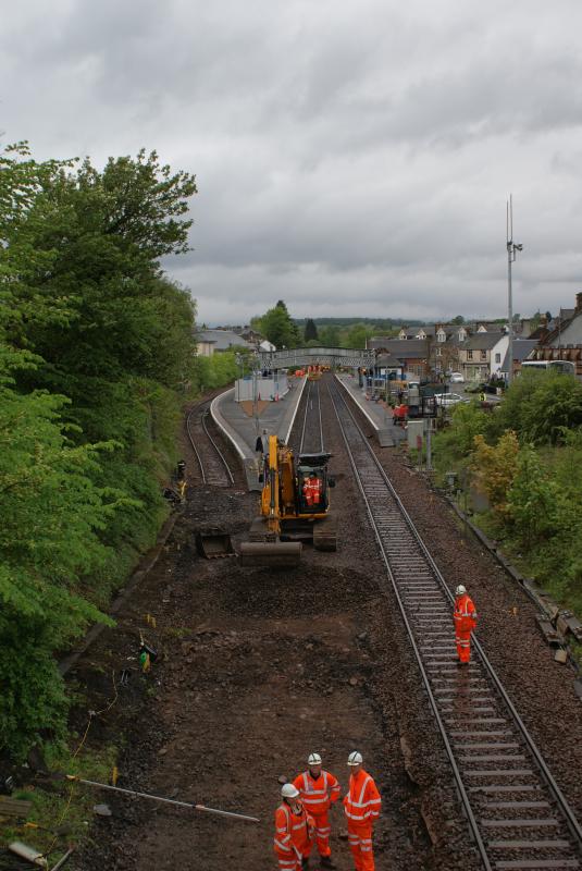 Track lowering at Dunblane 001: Track lowering for OHL clearance at B8033 overbridge Dunblane on 17.05.2014. Notice the pig-tails on the person on the left of the bunch of three. Photo of Track lowering at Dunblane 001