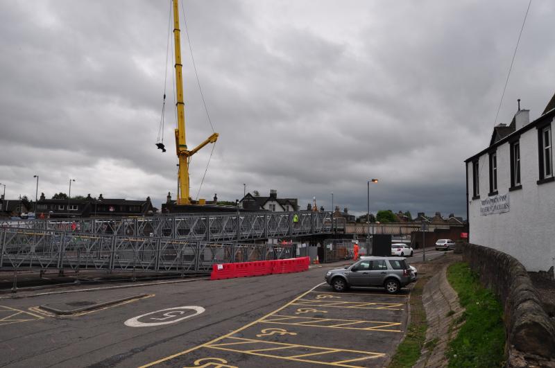 up up and away: Part of the main street bridge in Larbert is lifted out over the houses in Main street to a waiting artic lorry to take it away for scrap Photo of up up and away